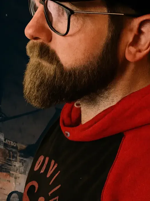Mario im Profil mit Brille, Bart und rotem Hoodie